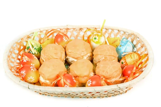 easter eggs and homemade sweet cakes in basket on white