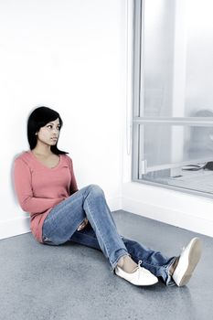 Depressed black woman sitting against wall looking out window