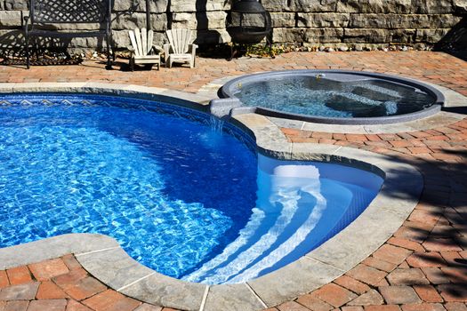 Outdoor inground residential swimming pool in backyard with hot tub