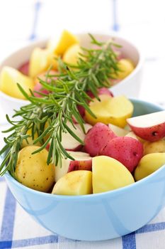 Bowl of cut raw small potatoes with skins and herbs ready for roasting