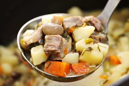 Hearty beef and potatoes stew with vegetables served with ladle