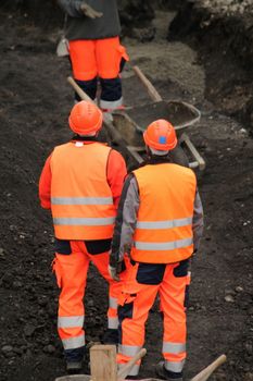 Workers wearing orange uniform talking on the construction site