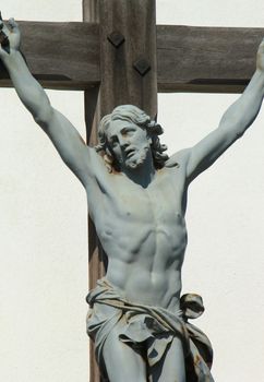 Close up of green statue of Jesus-Christ on a wood cross