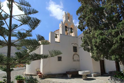Bell tower in the back of byzantine historical church of Panagia Episkopi by beautiful weather, Gonia, Santorini, Greece