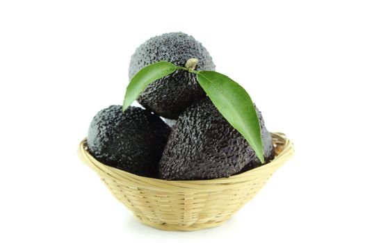 Avocados with leaves on a Dish of straw