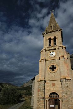 Facade and entrance of church Saint Michel Saint Mammes in the mountain by sunset, Cervieres, Alps, France