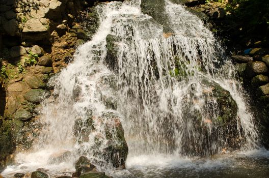powerful waterfall on rocky slopes in summer