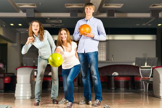 Group of young friends playing bowling, spending time with friends