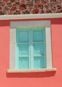 Green shutters closed on colorful home facade in Santorini, Greece