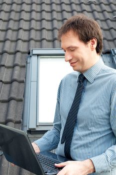 young man using a laptop against the window and roof