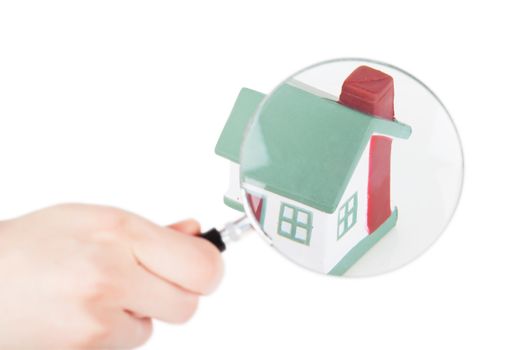 Toy of house and hand with magnifying glass isolated over white background
