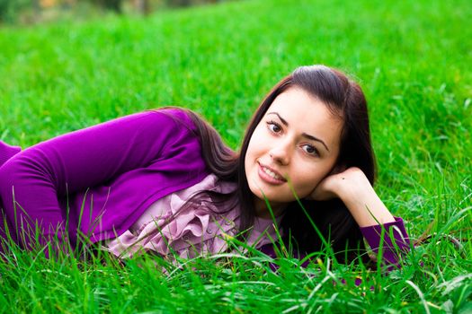 beautiful young woman lying on green grass