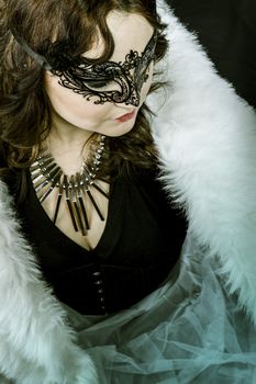 Beautiful woman with white feather dress and silver jewelry, black venetian mask