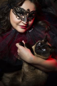 Woman with siamese cat, wearing venetian mask