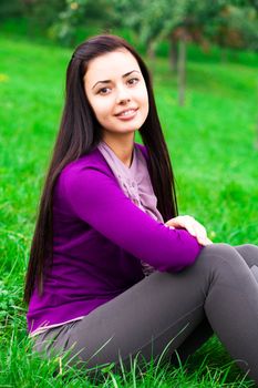 beautiful young woman sitting on green grass