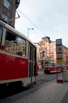 Two trams move the friend towards to the friend down the street Prague