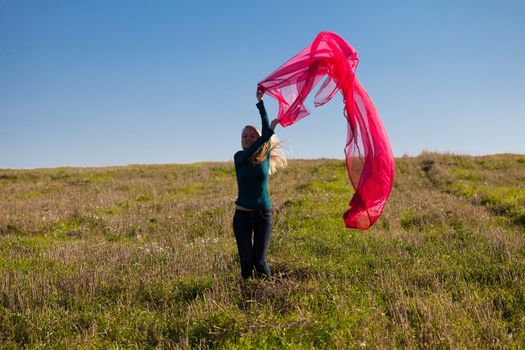 young beautiful woman jumping with tissue into the field against the sky