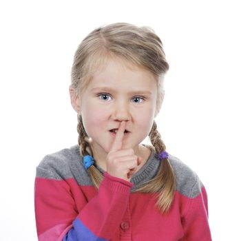 Portrait of little girl with silence gesture over white background