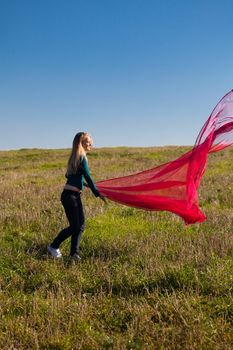 young beautiful woman jumping with tissue into the field against the sky