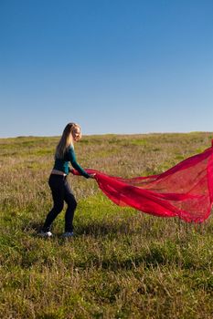 young beautiful woman jumping with tissue into the field against the sky