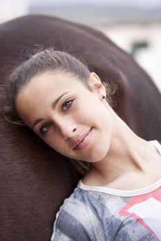 Pretty girl, dressed in an american flag tshirt, resting on her horse, looking at camera