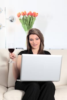 blond woman on sofa with computer and wine glass