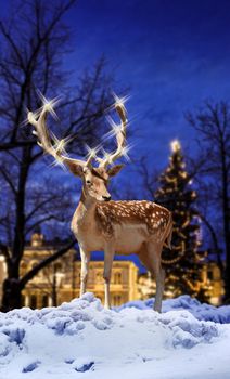 Christmas deer with illuminated star light horns in snowy town