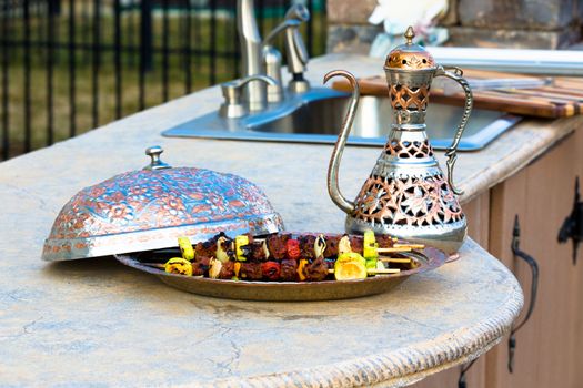 Shish Kebabs on outside kitchen concrete counter top presented in a Arabic style bowl.