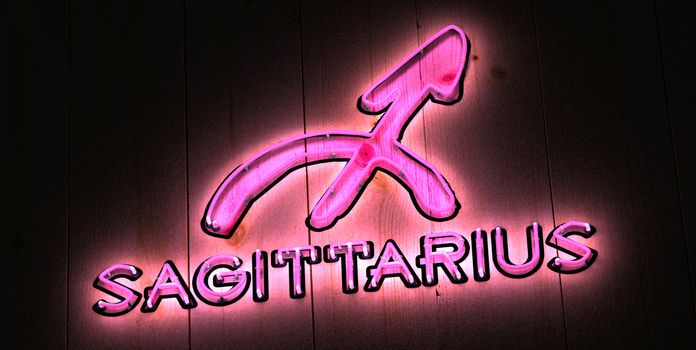 Pink Sagittarius Zodiac sign in glowing pink neon light with Sagittarius symbol
