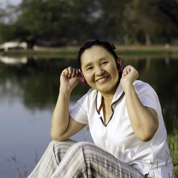 Beautiful asian woman listening music in headphones, outdoor portrait