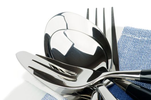 Arrangement of Silverware with Table Knife, Table Spoon, Fork, Dessert Spoon and Dessert Fork on Blue Napkin closeup