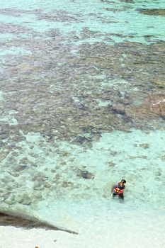 Young man   over coral reef in transparent tropical sea