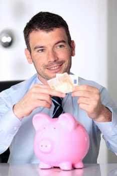 man in office with pink piggy bank