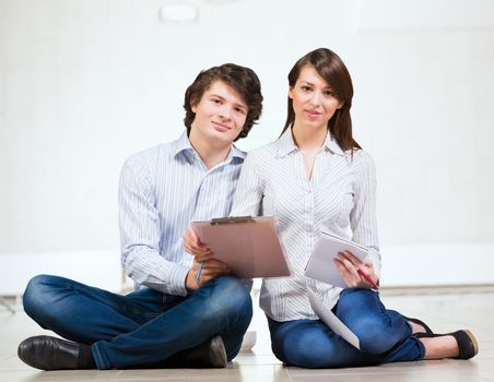 Attractive young man and woman sitting on the floor talking