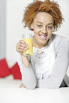 Attractive black woman  relaxing in living room with a glass of juice