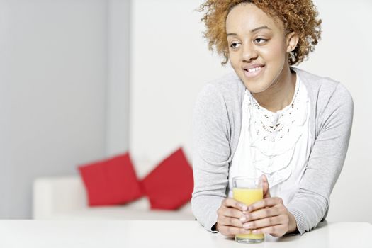 Attractive black woman  relaxing in living room with a glass of juice