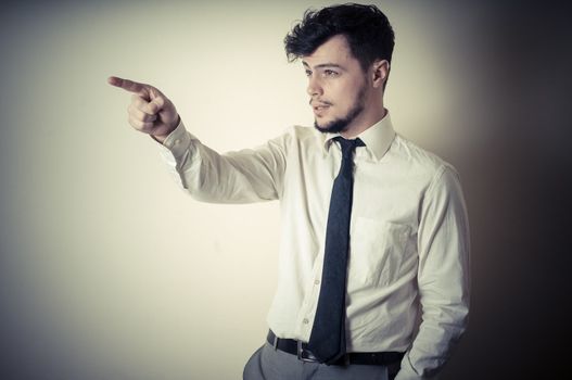 stylish modern guy with white shirt pointing on gray background