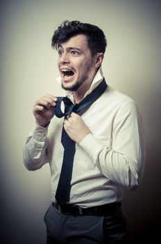 Sexy stylish businessman adjusting tie on gray background