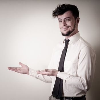 stylish modern guy with white shirt pointing on gray background