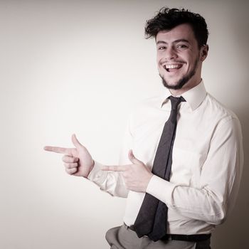 stylish modern guy with white shirt pointing on gray background