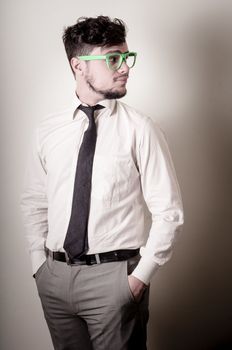 Sexy stylish businessman adjusting tie on gray background