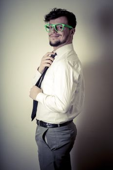 Sexy stylish businessman adjusting tie on gray background