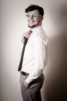 Sexy stylish businessman adjusting tie on gray background