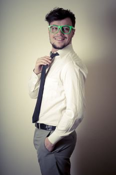 Sexy stylish businessman adjusting tie on gray background