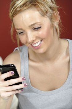 Beautiful young woman lying on sofa at home reading a text message.