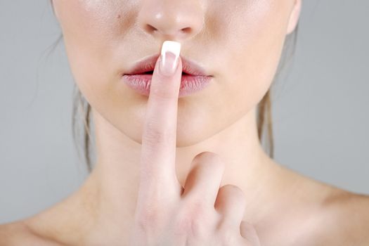Young woman in a beauty style pose with a finger over her mouth