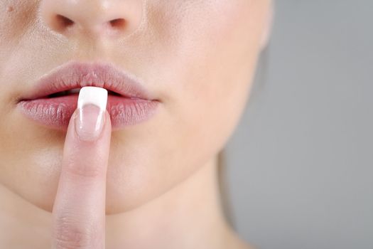 Young woman in a beauty style pose with her finger over her mouth