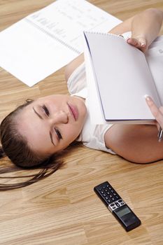 Young woman working from home reading documents while lying on the floor