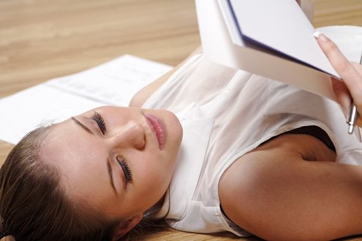 Young woman working from home reading documents while lying on the floor