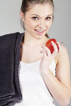 Young woman resting after exercise in fitness wear eating an apple